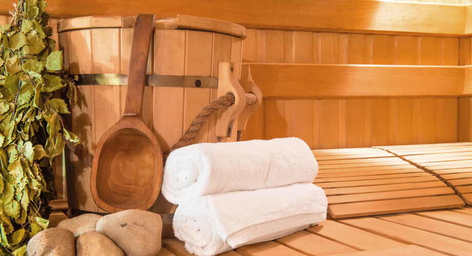 Ein Blick in eine Sauna in der Handtücher und ein Aufgusseimer drapiert sind