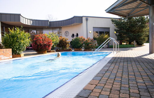Ein Blick auf das Aussenschwimmbecken in dem ein Frau schwimmt