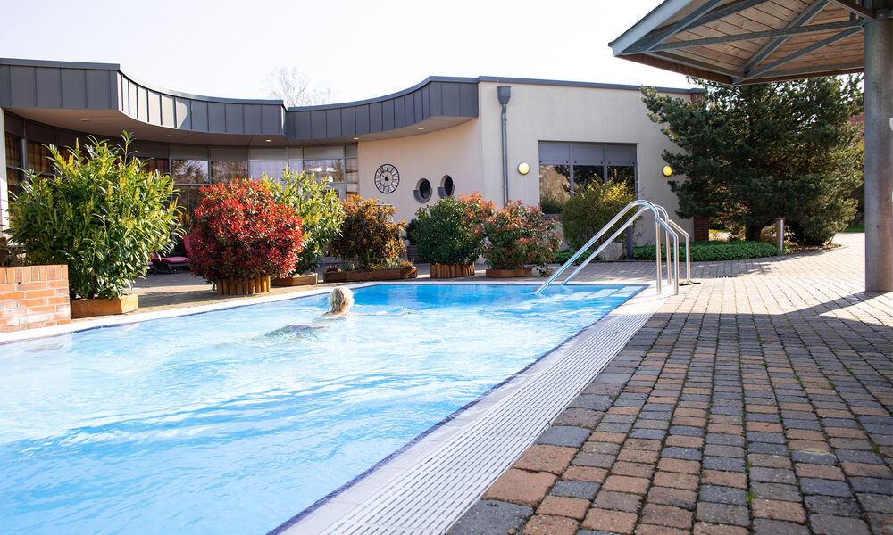 Ein Blick auf das Aussenschwimmbecken in dem ein Frau schwimmt